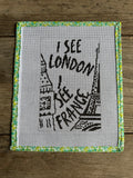 Cross-stitched design on fabric with 'I see London' text and skyline, framed by a decorative border.
