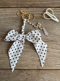 Keychain with polka dot bow and pearl details on a wooden surface