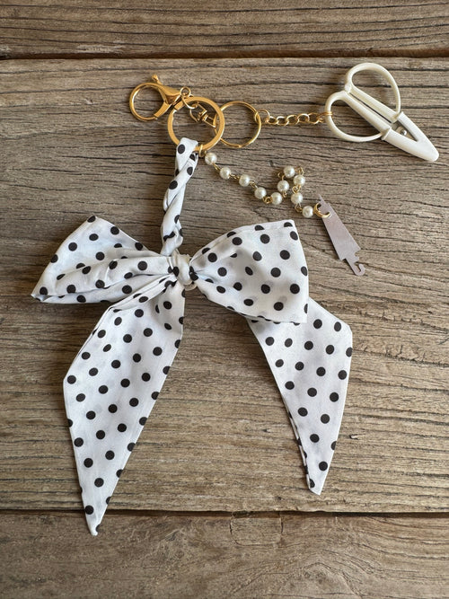 Keychain with polka dot bow and pearl details on a wooden surface