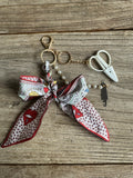 Keychain with a patterned scarf and small scissors on a wooden surface