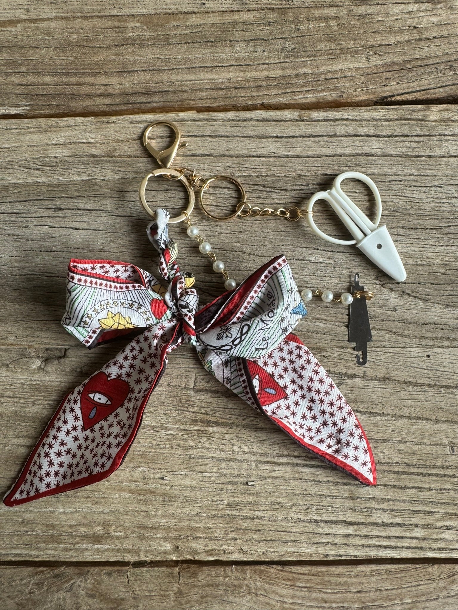 Keychain with a patterned scarf and small scissors on a wooden surface