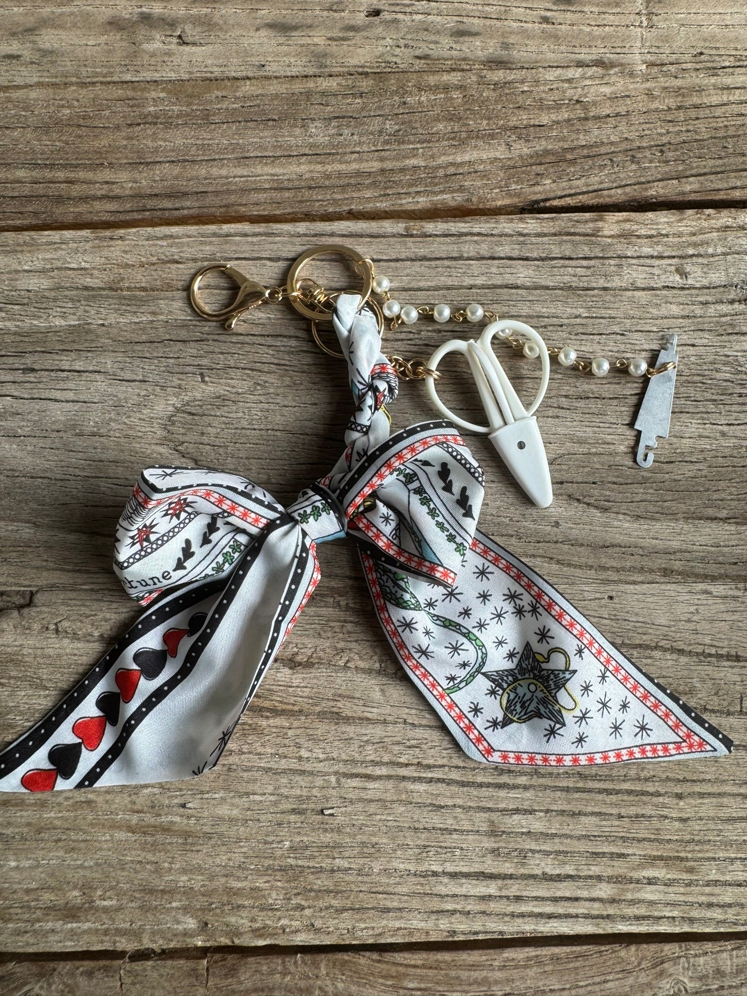 Keychain with decorative ribbon and scissors on a wooden surface