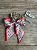 Keychain with floral ribbon and scissors on a wooden surface