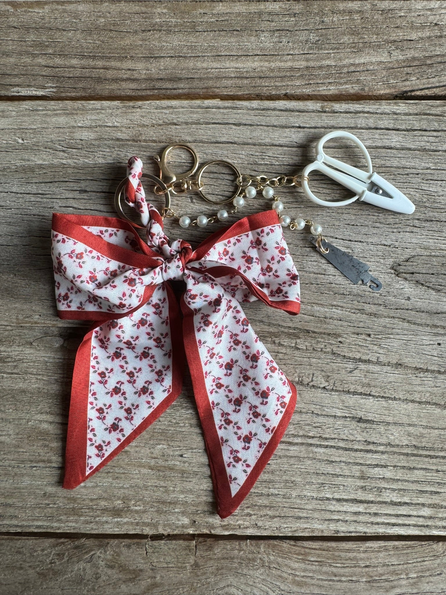 Keychain with floral ribbon and scissors on a wooden surface