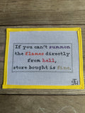 A square cross-stitch sampler with a yellow border, featuring a humorous embroidered quote on white Aida cloth, displayed flat on a rustic wooden background.