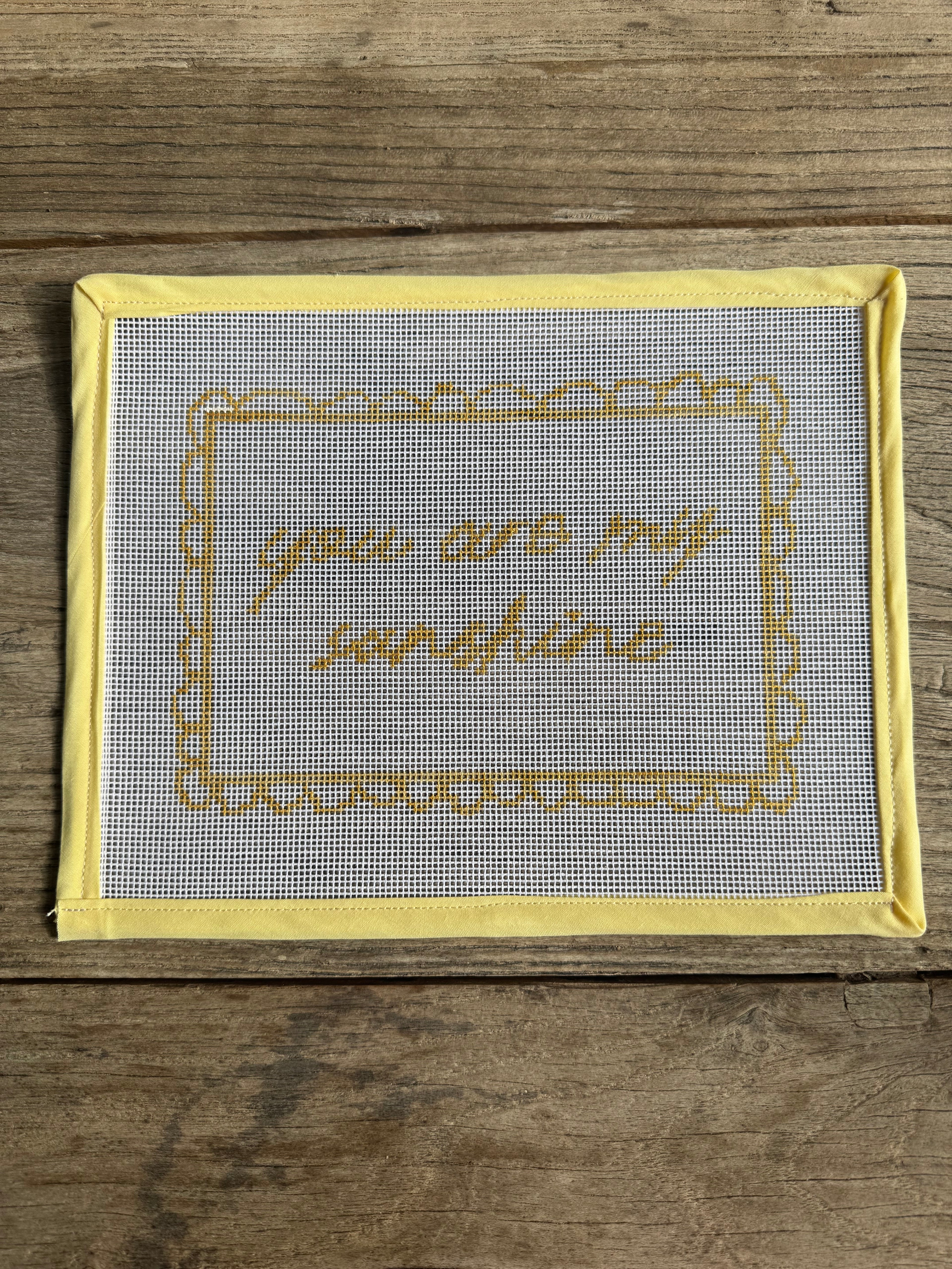 Decorative mesh panel with embroidered text on a wooden surface
